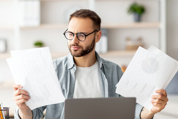 Poster - Serious young man looking through documents while having online business meeting at home office. Focused male freelancer making web presentation, communicating remotely on laptop