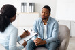 © Prostock-studio - Unhappy young black man having session with professional psychologist at mental health clinic. Psychotherapist taking notes during conversation with depressed male patient