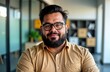 © Pete - Latin man in office setting Mexico City. Friendly plus size business pro looking at camera. He wears casual attire and glasses. Modern workplace. Portrait photo.
