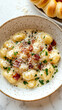 © PoodPhoto - Delicious creamy gnocchi topped with crispy bacon bits and fresh herbs in a rustic bowl.