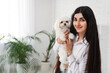 © Pixel-Shot - Young woman holding her white Bolognese dog in office