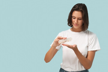 Wall Mural - Pretty young woman with pill organizer on blue background