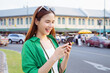 © sitthiphong - Cheerful beautiful Asian woman holding smartphone and camera with looking for tourist attractions.