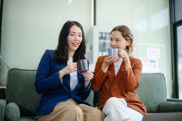 Wall Mural - Two women collaborating on a project on sofa at home, brainstorming with a laptop and notebook