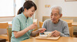 © ibosa - 高齢者に食事を補助する介護士