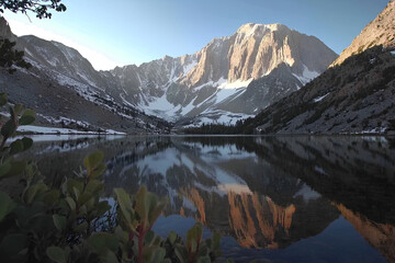  Snowy mountains of the Snowy Range reflect in the crystal-clear waters of a lake, creating a mesmerizing landscape. Perfect for imagery about nature and mountains