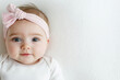 © Tetyana - Cute baby girl with blue eyes and pink headband lying on white blanket. Adorable baby girl lying on white blanket wearing pink headband