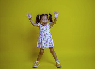 Little Girl in Dress and Sneakers Posing on Bright Yellow Background