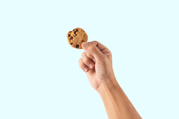 male hand holding a cookie isolated on cyan background