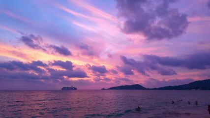 Wall Mural - A captivating scene of a vibrant sunset over the ocean, with hues of pink, purple, and orange blending in the sky. Silhouettes of swimmers enjoy the water while a cruise ship sails near the horizon