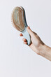 © SHOTPRIME STUDIO - Hand holding a brush with a comb attached to the end of the bristles
