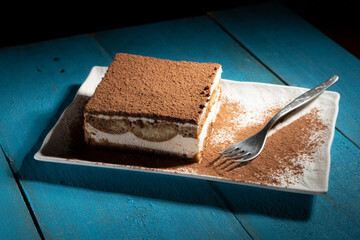 Wall Mural - Tiramisu cake dessert served with coffee, biscuit and cocoa on dark background.spoon. Dessert. Food Concept