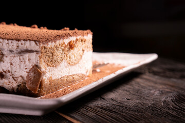 Wall Mural - Tiramisu cake dessert served with coffee, biscuit and cocoa on dark background.spoon. Dessert. Food Concept