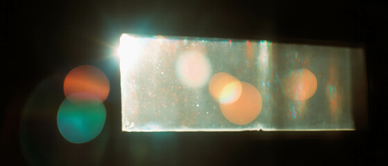 Poster - Light leaks creating vibrant lens flares against a black background from a window