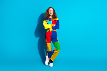 Wall Mural - Cheerful young woman in colorful denim clothing standing against a vibrant blue background, expressing confidence and happiness