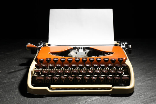 Vintage typewriter with sheet of paper on black background