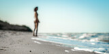 swimsuit in the sand on the beach near the sea surf on the background of a naked female figure and blue sky