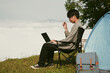 © doidam10 - Young business man working computer on peak hill. Hiker online shopping on laptop at sunset, sunrise on top mountain, freelance person remote work with digital tablet. travel vacation holiday concept