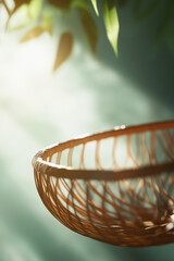 Poster - Woven basket with sunlight and blurred green leaves in the background, symbolizing simplicity, natural beauty, and eco-friendly living.