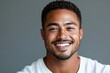 © Surachetsh - A black African man in white casual attire, smiling against a gray background, projects warmth and approachability with a charming demeanor.