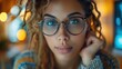 © anatolii - Focused young woman with curly hair and glasses in a cozy indoor setting during evening hours, engaging in thoughtful reflection or study
