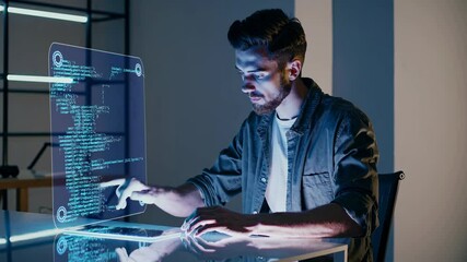 Fototapete - Young man coding at a modern workstation with holographic interface in a tech-focused environment during evening hours