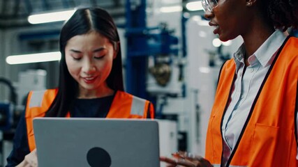 Aufkleber - Two women collaborate on a project in a manufacturing facility while wearing safety vests and using a laptop
