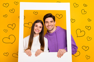 Poster - Photo of attractive lady handsome guy hold picture frame beaming toothy smile isolated on yellow color background