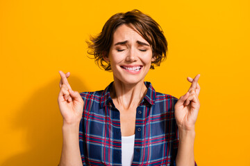 Wall Mural - Photo of nervous worried woman with short hairdo dressed plaid shirt hold fingers folded make wish isolated on yellow color background