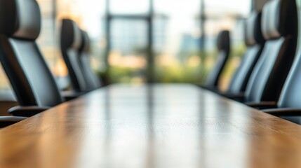 Poster - Wooden conference table with polished surface in foreground and blurred modern business office with large windows and ergonomic chairs in background