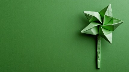 Poster - Green origami pinwheel on a vibrant green background, symbolizing creativity and eco friendliness, perfect for promoting sustainability and children s activities