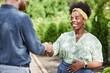 © Seventyfour - Excited African American female landscape designer giving firm handshake to male partner making deal on business project while meeting outside in garden, scene bathed in sunlight, copy space