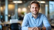 © Tondone - A confident young man smiles while seated at a modern office desk, embodying professionalism and approachability in a bright, contemporary workspace.