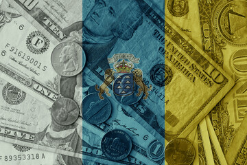 Wall Mural - colourful flag of canary islands on a dollar money banknotes and coins background. finance concept. macro shot