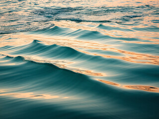 close-up of the ocean's surface under a cloudy sky, featuring deep gray-blue waves with silvery refl