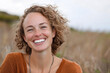 © perfectlab - Smiling woman in a field on a sunny day