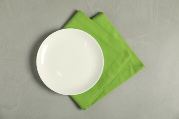 Wall Mural - Green napkin and empty plate on grey table, top view