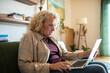 © Marko Geber - Shocked middle aged woman using laptop at home