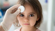 © Bonsales - Doctor wearing gloves applying a compress on the forehead of a little girl with a swollen eye, providing medical care and treatment in a healthcare setting