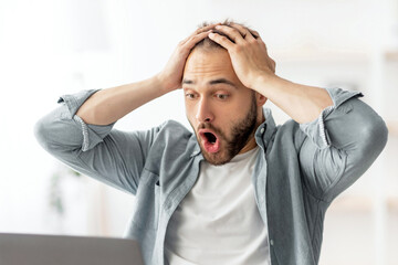 Poster - Terrified male freelancer looking at laptop screen, grabbing his head, making error in business project, missing deadline at home office. Young man having workplace stress, finding mistake in document