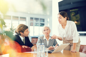 Wall Mural - Adult man, elderly woman and young woman in business clothes having meeting in office