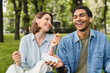 © InsideCreativeHouse - Mixed-race students friends romantic couple freelancers listening to the podcast radio music favorite singer song playlist in earbuds earphones using musical application walking in city park outdoors