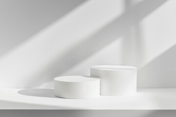 Poster - Two white cylindrical podiums of different sizes are displaying products on a white surface with a white wall background and window sunlight creating shadows