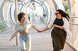 © ADDICTIVE STOCK - Joyful lesbian couple running on a modern urban bridge holding hands