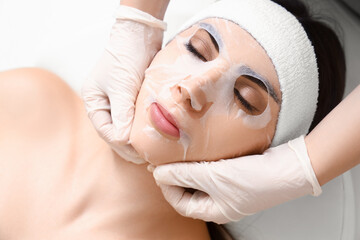 Wall Mural - Young woman with facial sheet mask relaxing in spa salon