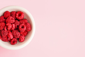 Wall Mural - bowl with delicious freeze-dried raspberries on pink background