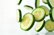 © miss irine - Fresh zucchini slices suspended in mid-air. Vibrant green slices, visible yellow insides offer close-up view. Water droplets suggest recent washing preparation. White background creates stark