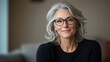 © Tondone - A confident woman with gray hair and glasses smiles warmly, showcasing her elegance and wisdom. The soft background highlights her calm demeanor and inviting personality.