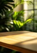 © artwiyanastudio - Sunlight illuminates a wooden table against a blurred backdrop of lush green foliage.
