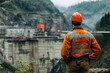 © EUT - Construction worker in orange safety gear overlooks a dam under construction. Image ideal for articles about engineering, infrastructure, and large-scale projects.